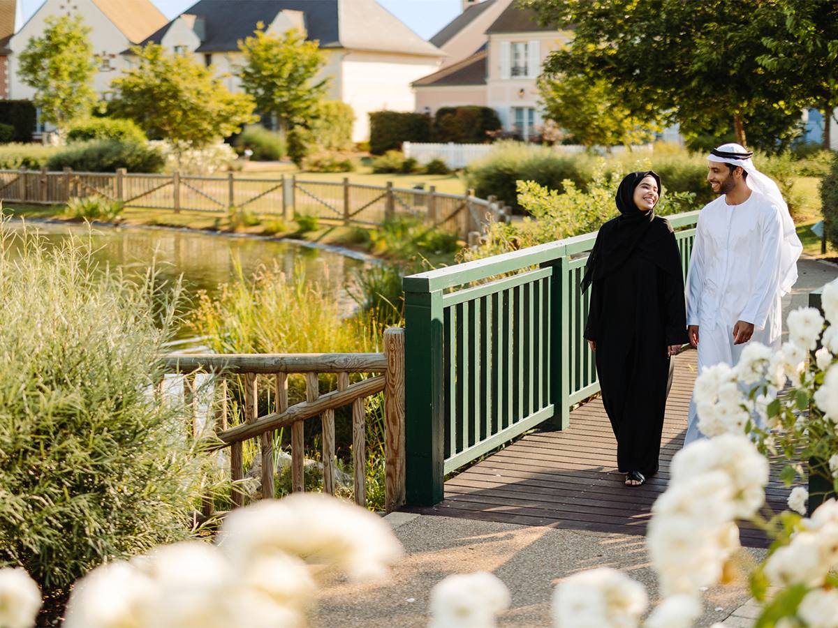 Couple walking across a bridge in lush gardens